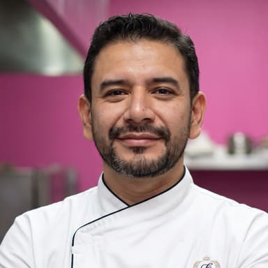 Chef Jaime, head and shoulders, in a white chef's jacket in the kitchen.